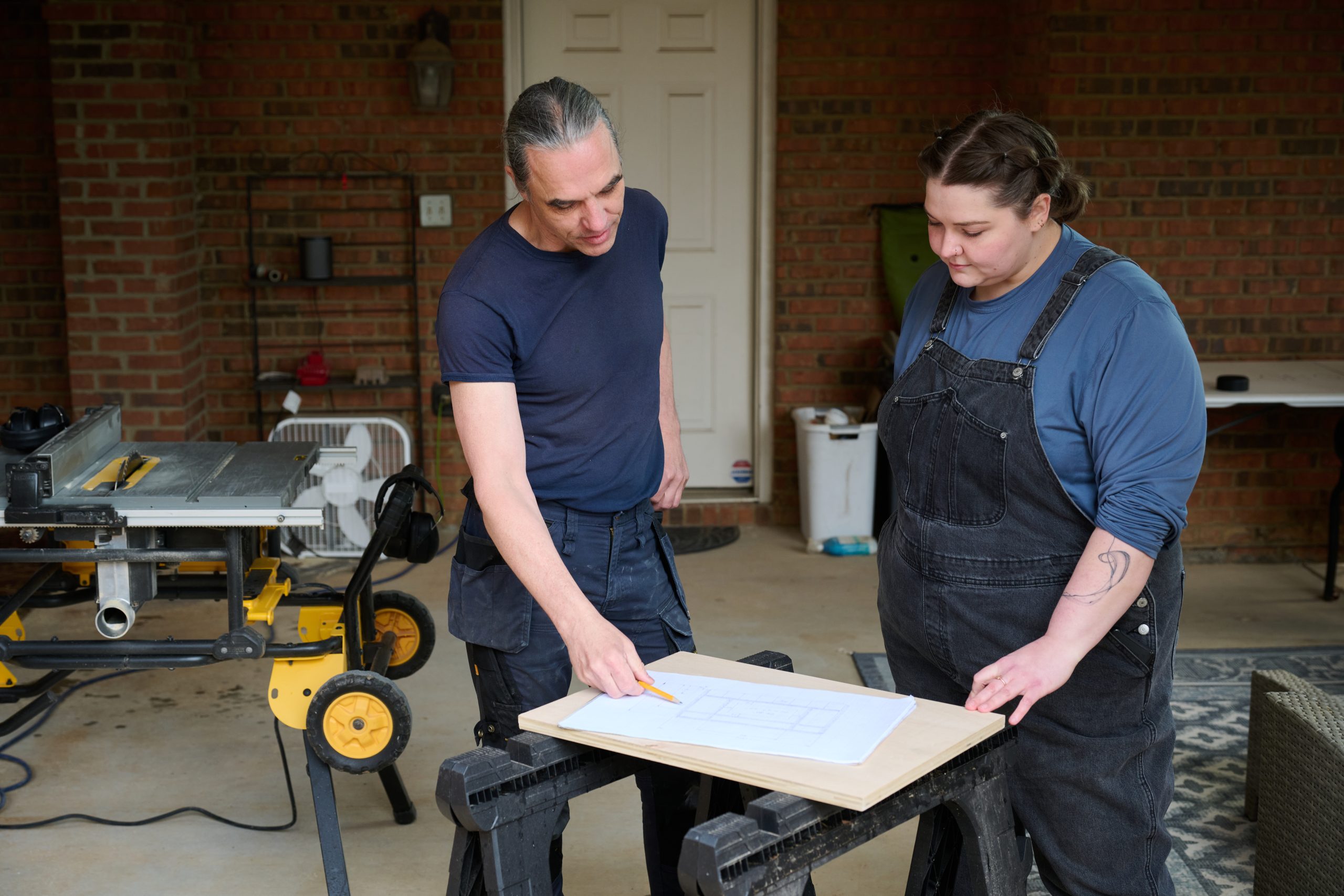 Caucasian male and female reviewing construction plans on a sawhorse
