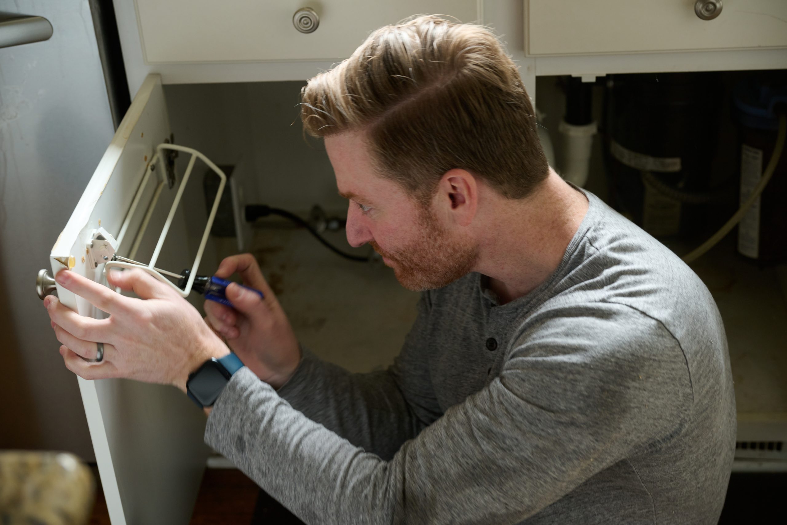 Caucasian male fixing shelving on the inside of cabinet door
