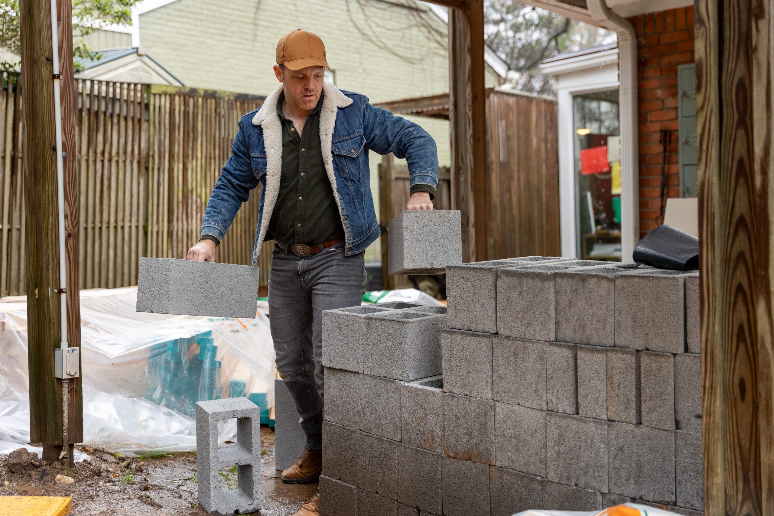 Caucasian male stacking cinder blocks on a job site