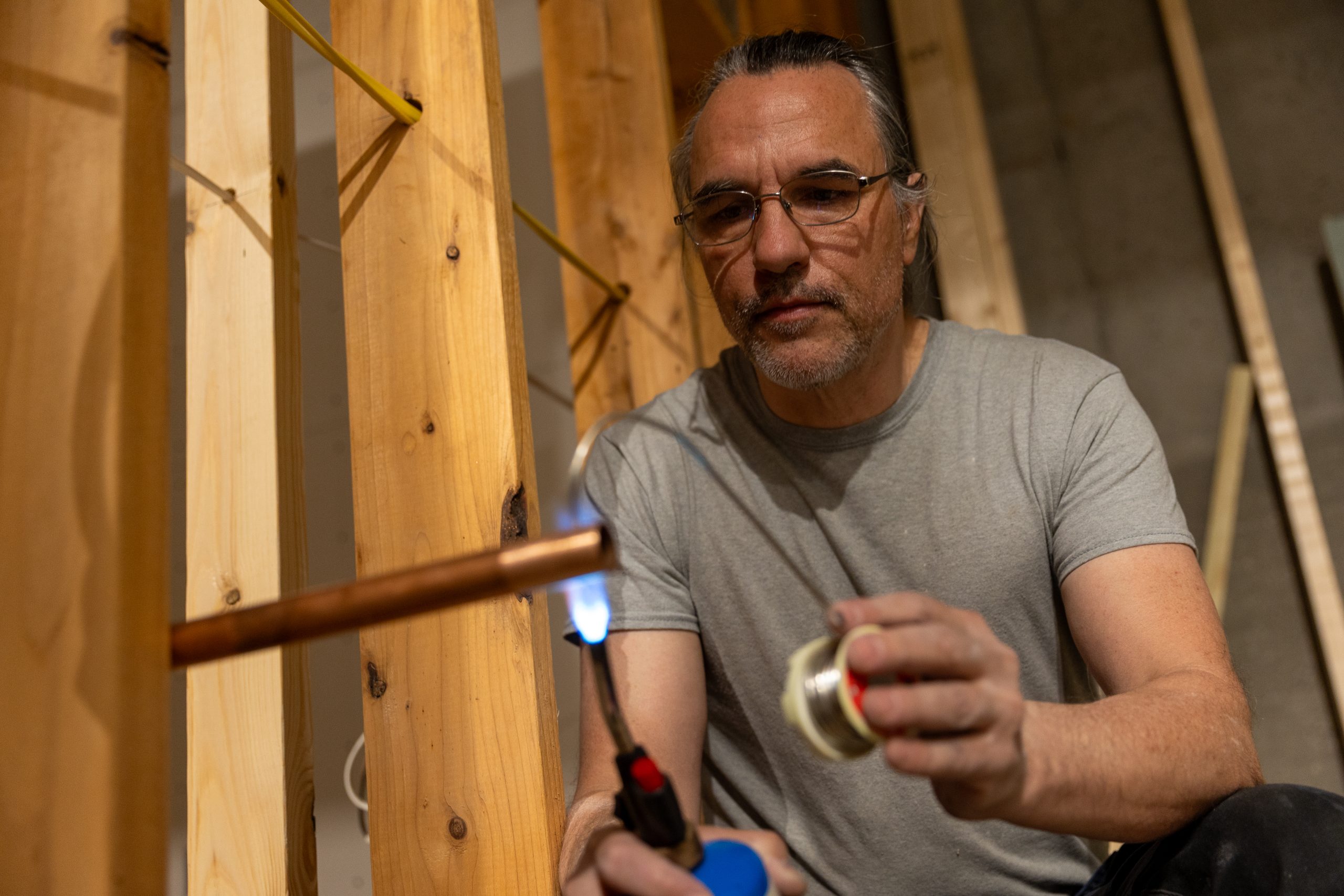 Caucasian male welding a copper pipe